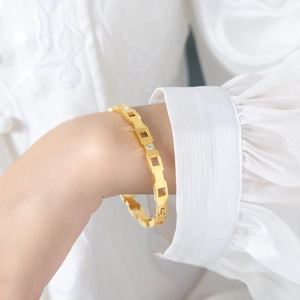 Detalle de brazalete chapado en oro de 18k con eslabones geométricos y circonitas