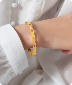 Detalle de un brazalete hueco geométrico chapado en oro 18k con circonitas en la muñeca
