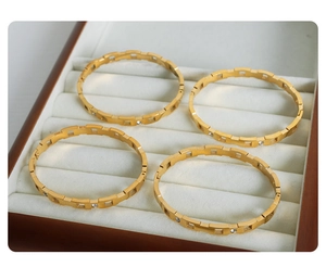 Detalle de cuatro brazaletes geométricos bañados en oro 18k con circonitas incrustadas