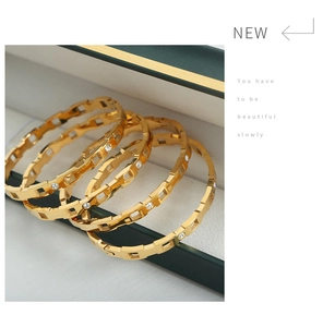 Detalle de cuatro brazaletes de acero de titanio chapados en oro 18k con circón