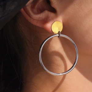Boucles d'oreilles créoles bicolores en or 18k et acier inoxydable portées par un mannequin