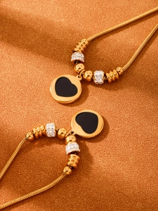 Gros plan d'une chaîne serpent dorée avec pendentif cœur émaillé et zircons