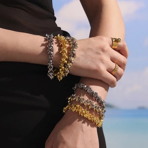 Golden and silver heart pendant bracelets with rings set against a seaside backdrop