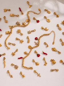 Detailed macro of gold-plated stainless steel charms featuring sea shells and clovers