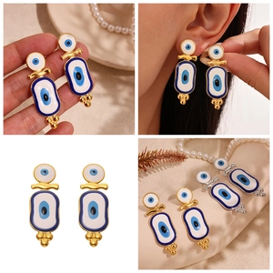 Detailed views of gold and silver evil eye enamel drop earrings in bohemian style