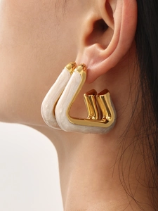 Close-up of geometric U-shaped gold earrings with white marble texture on female model