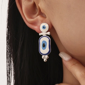 Boucles d'oreilles œil maléfique en acier inoxydable et émail bleu sur mannequin