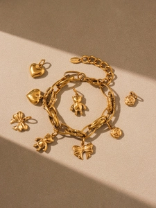 Detail of gold-plated stainless steel charm bracelet with bear and heart pendants