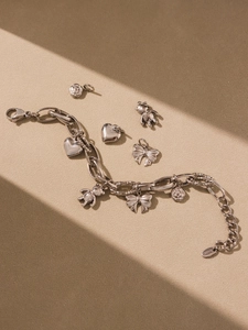 Detailed macro of silver stainless steel chain bracelet with bear and bow charms