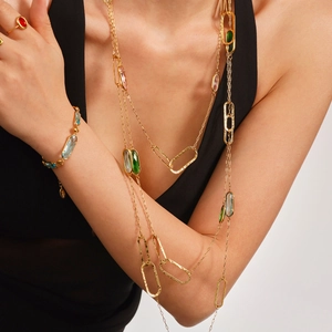 Goldenes Halsketten- und Armbandset mit bunten Edelsteinen auf einem schwarzen Trägertop