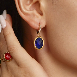 Elegant gold earrings with sparkling blue oval gemstones and matching red crystal ring