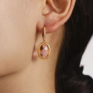 Elegant gold earrings with oval pink crystal and sparkling pave zircons on female model