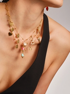 Detail of layered gold necklace with colorful enamel bells and lucky clover charms