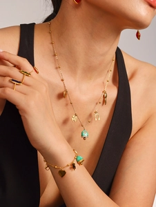 Detail of bohemian gold layered jewelry set with colorful enamel charms on a model