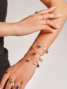 Detail of gold bracelets with colorful enamel charms and heart pendants on wrist