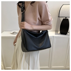Close-up of minimalist black matte leather crossbody bag with wide adjustable strap detail