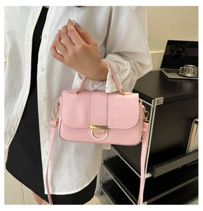 Pink leather handbag detail showing adjustable shoulder strap and gold hardware on model
