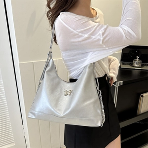 Silver metallic PU hobo bag with butterfly buckle and chain strap shown on model shoulder