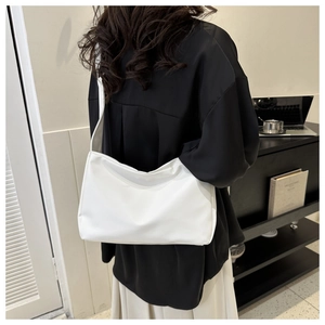 Close-up of white minimalist hobo shoulder bag with matte leather and wide strap detail