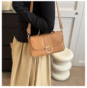 Close-up of light brown crossbody bag with gold metal buckle shown on a model