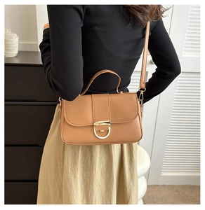 Detail of camel retro handbag featuring a gold D-ring buckle and slim shoulder strap