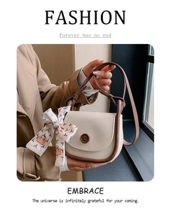 Detail of beige square bag with brown trim and geometric print silk scarf handle