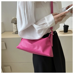 Model wearing rose pink crossbody bag with adjustable strap and soft leather texture