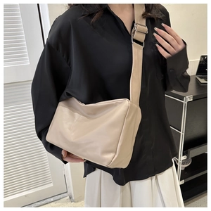Detail shot of beige faux leather crossbody bag with wide strap and silver metal buckle