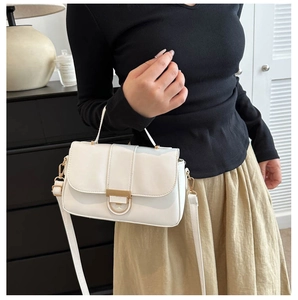 Detail of white leather handbag with golden arc clasp and stylish top handle design