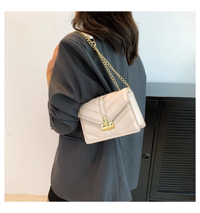 Dettaglio borsa a tracolla beige chiaro con trama trapuntata a V e catena dorata