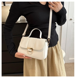 Close-up of cream white PU leather handbag with golden semicircular metal clasp detail