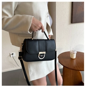 Detail of black matte leather handbag with gold hardware and stylish white buckle decoration