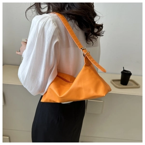 Detail view of the vibrant orange shoulder bag with adjustable strap and gold metal buckle