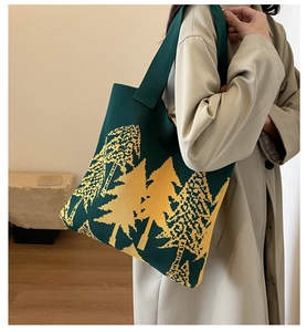 Detail of green knitted tote bag with yellow forest pattern worn with a khaki trench coat