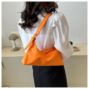 Detail of orange matte hobo bag with adjustable strap shown on a model in daily outfit
