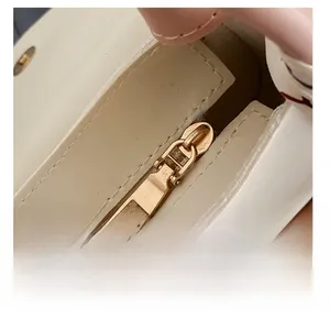 Macro detail of high-quality golden metal zipper and magnetic snap closure on a cream bag