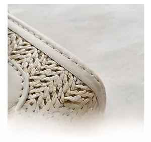 Macro detail of beige woven texture and precise leather stitching on shoulder bag