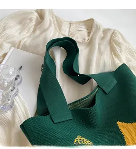 Detail of dark green knit tote bag with yellow star pattern and reinforced handles