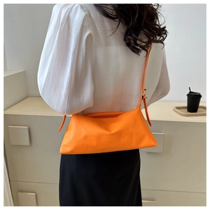Detail of soft orange PU leather bag showing adjustable shoulder strap and top zipper