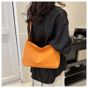 Detail of a minimalist bright orange crossbody bag in lightweight nylon fabric material