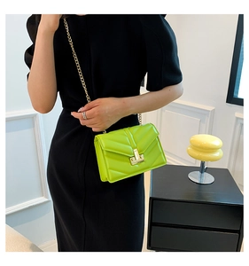 Borsa a busta trapuntata verde neon con catena dorata indossata da modella in stanza moderna