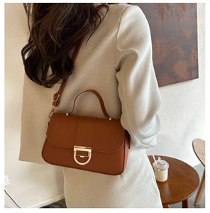 Brown retro leather handbag with vintage gold and ivory buckle worn over the shoulder