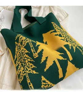 Detail of green and yellow knitted tote bag with abstract forest tree pattern on white fabric