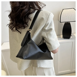 Detail of matte black leather shoulder bag with gold metal buckle on adjustable strap