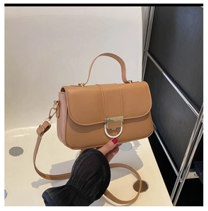 Detail of light brown crossbody bag featuring gold metal clasp and sleek faux leather