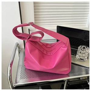 Detail of pink faux leather tote bag with adjustable strap on a modern metal shelf