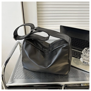 Close-up of a soft black leather crescent crossbody bag with silver hardware on a metal cart