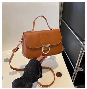 Detail of caramel faux leather bag featuring a gold D-buckle and adjustable strap
