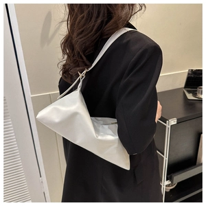 Detailed side view of white geometric PU leather shoulder bag worn by model in a minimal room