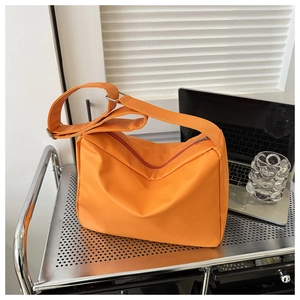 Macro detail of an orange hobo shoulder bag with matte leather texture and silver buckle